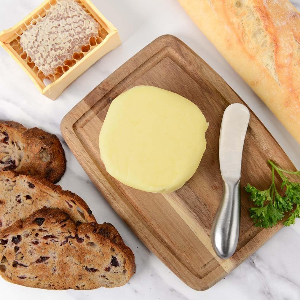 Manteiga artesanal sobre tábua de madeira com pães